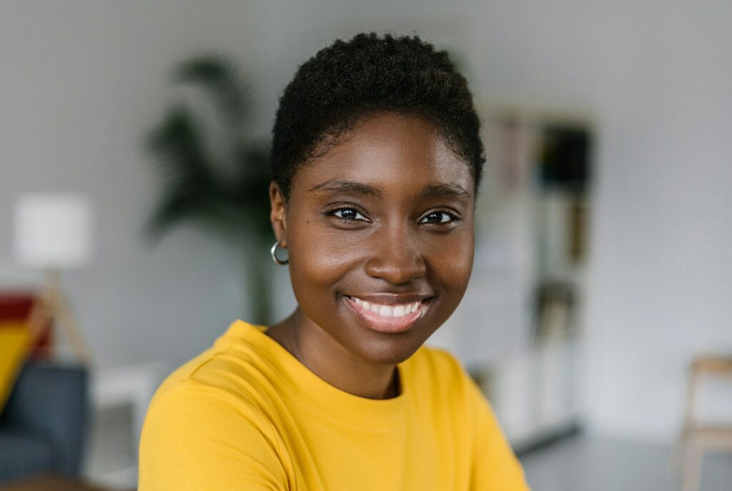 Portrait of smiling millennial african woman standing at home