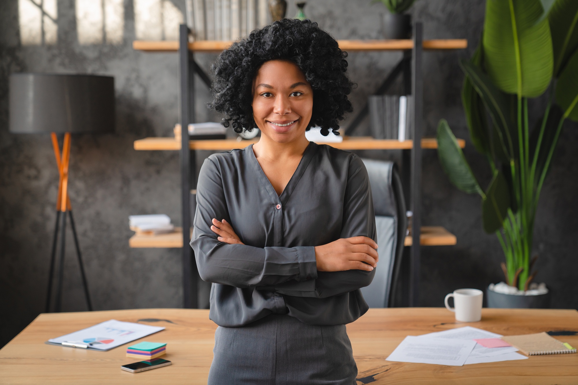 Smiling African business woman pose cross-armed in company office staring at camera.