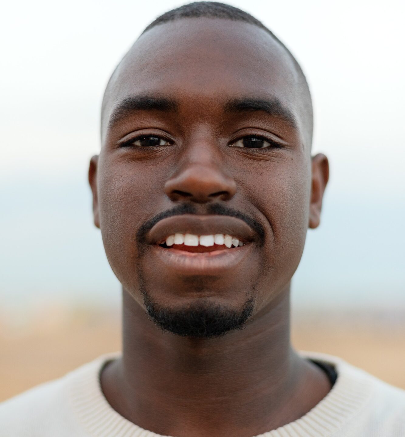 Vertical portrait of young African American man looking at camera. Headshot.